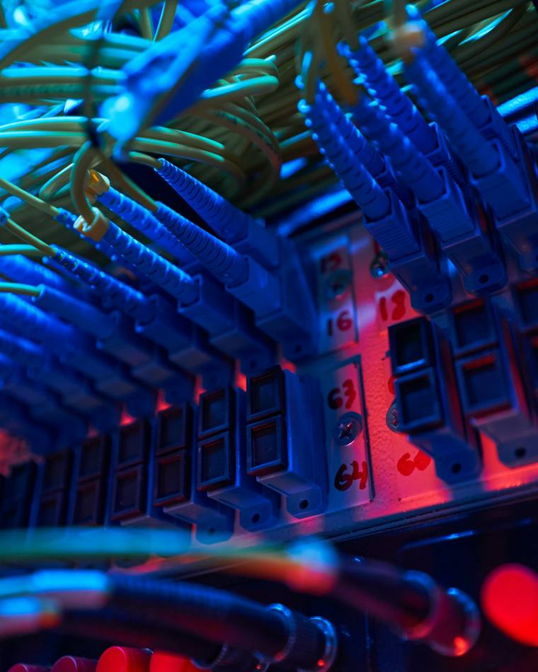 Fiber patch cords with LC connectors terminated into a patch field, ports marked by hand.