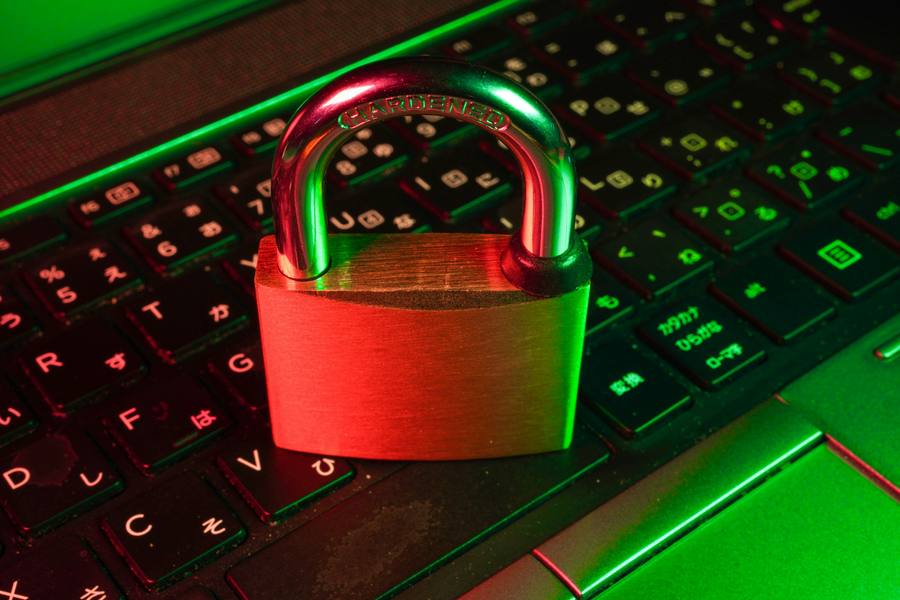 A brass padlock resting on a backlit laptop keyboard.